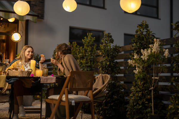 Jóvenes amigos cenando en el patio trasero de la casa de campo al anochecer